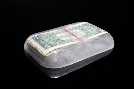 Bundle of dollar cash frozen inside a block of ice