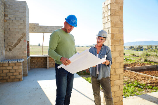 Architect and builder discussing blueprints on a construction site