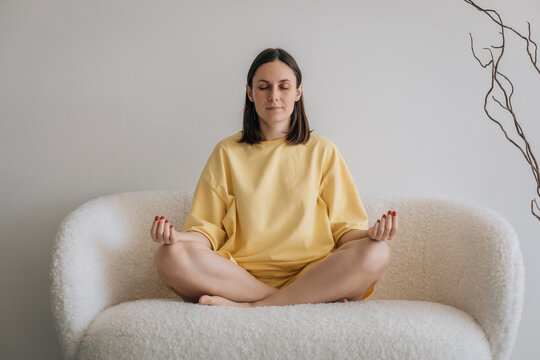 Woman meditating on sofa at home