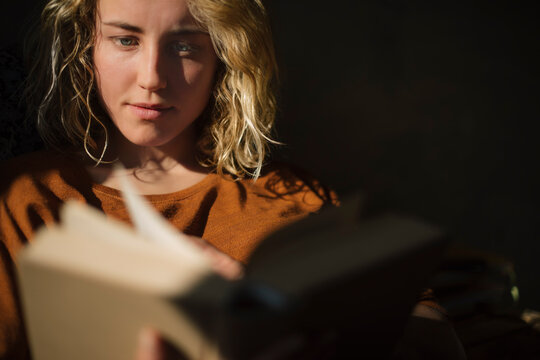 Blond young woman reading a book