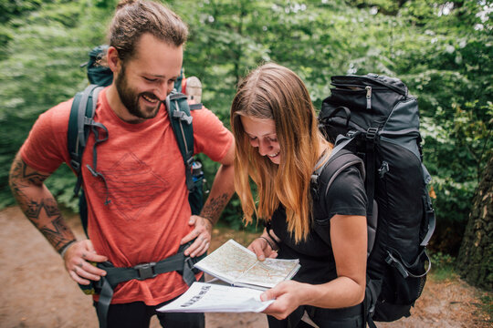 Happy young couple on a hiking trip reading map