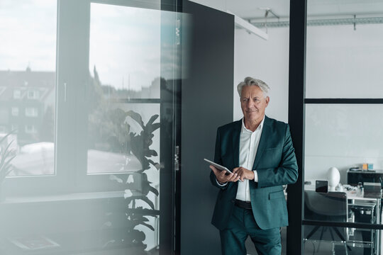Smiling businessman using digital tablet while standing at office