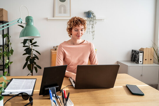 Businesswoman working efficiently at desk with multiple computer screens