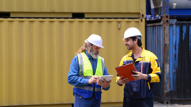 Shipping supervisors discussing freight container management at commercial logistics terminal.