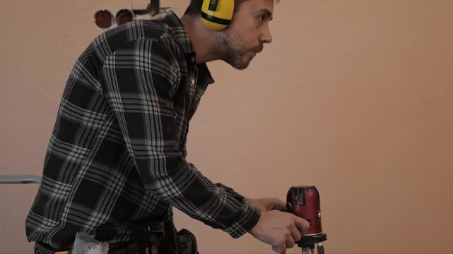 Worker performs precise marking with laser level preparing wall chases for electrical cable installation in construction site