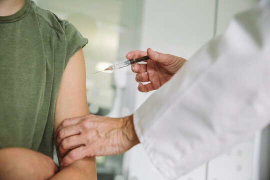 Doctor injecting vaccine into arm of teenager