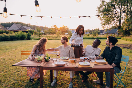 Diverse friends enjoying outdoor dinner party at sunset