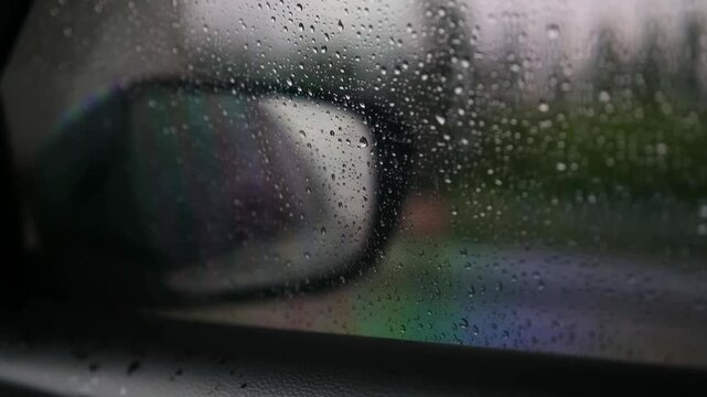 Raindrops on a car window with reflection of side mirror