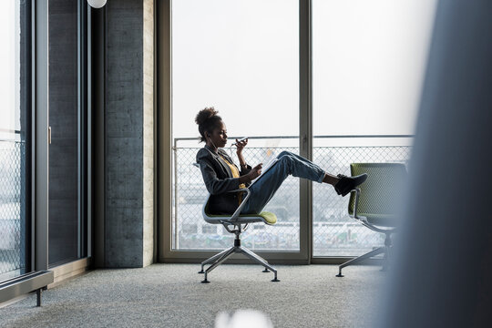 Businesswoman sitting on office chair using cell phone