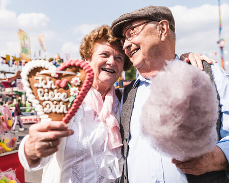 Portrait of happy senior couple with gingerbread heart and cotton candy on fair