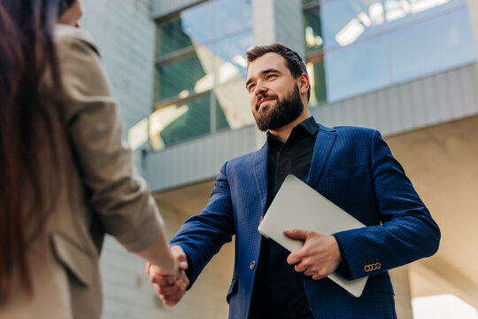 Boss shaking hands with job seeker outside corporate building