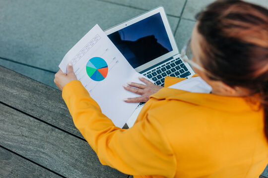 Businesswoman working outdoors on laptop analyzing business strategy
