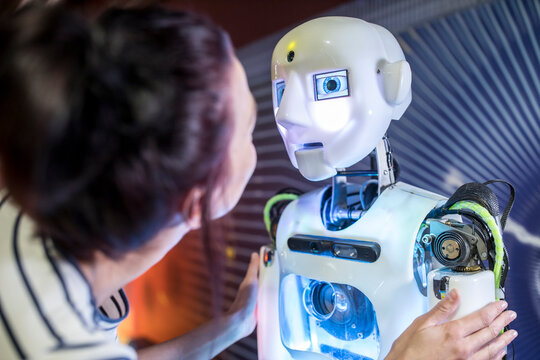 Tech developer looking at human robot in workshop