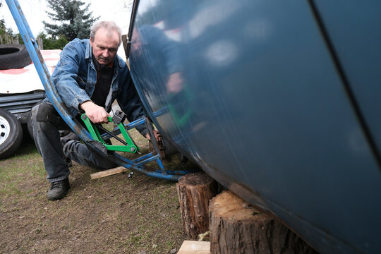 Hobbyist repairing a vehicle in a garden in Poland