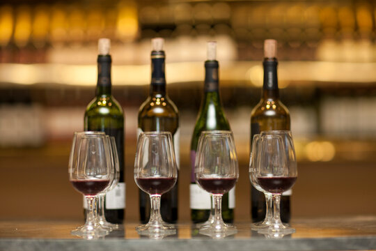 Red wine glasses and wine bottles on a counter of a wine cellar