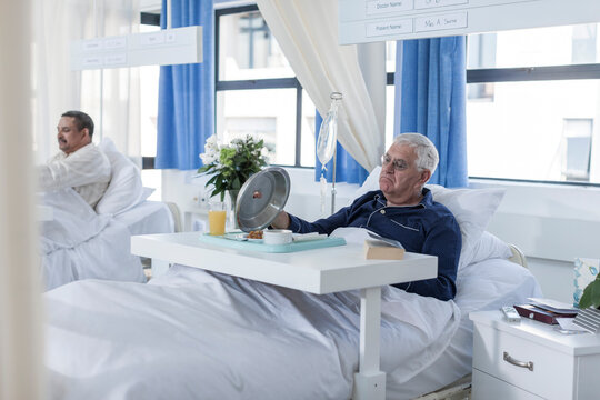 Senior patient in hospital bed looking at meal