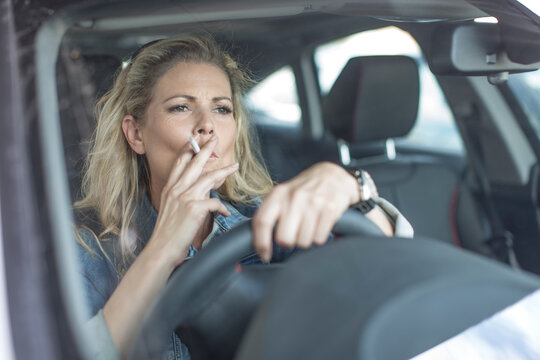 Serious woman in car smoking a cigarette