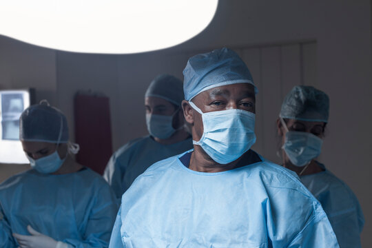 Portrait of surgeon wearing mask with team in background
