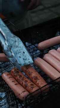 Vertical video. Summer weekend activity, barbecue, cookout. Grilling sausages during summer picnic