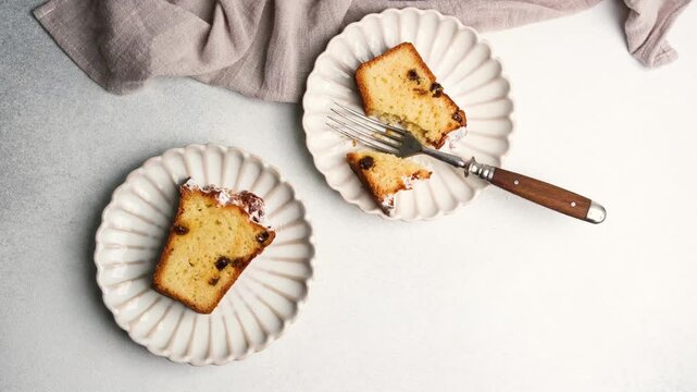 Two slices of raisin cake on white plates with a fork