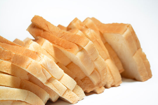 Fresh white bread slices arranged in a diagonal stack on a clean white background, highlighting the soft texture and golden crust.