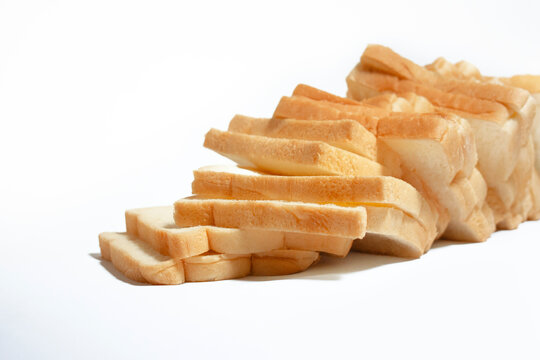 Multiple slices of white bread aligned in a diagonal stack, creating a simple bakery food composition on a clean white background.