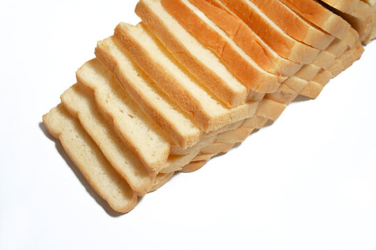 Top view of multiple slices of white bread arranged in a diagonal overlapping stack on a clean white background.