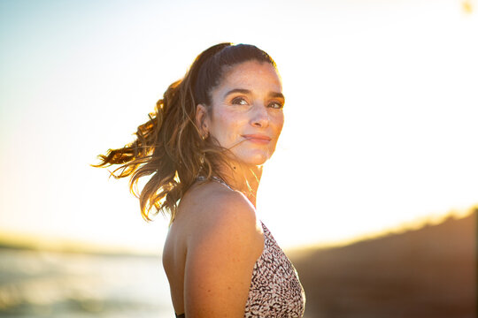 Confident woman looking back at sunset on the coast