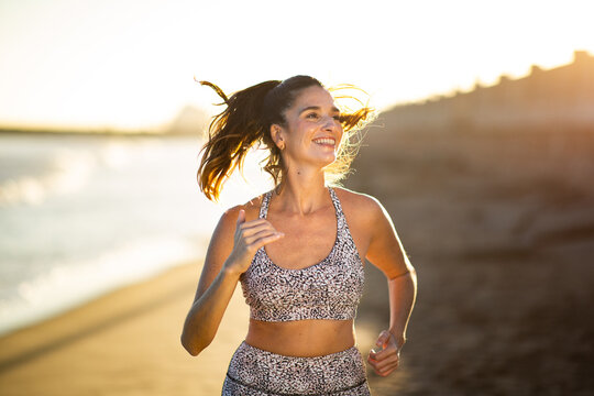Happy woman running on beach at sunrise