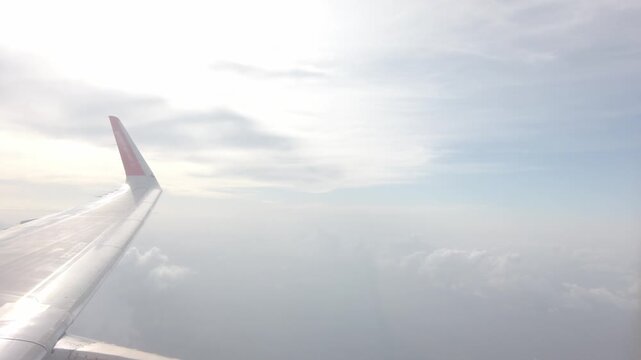 view from plane window of airplane's engine while airplane flying over sky cloudscape with long wing with winglet. plane window view Plane wing flying over sea of clouds on cloudy day