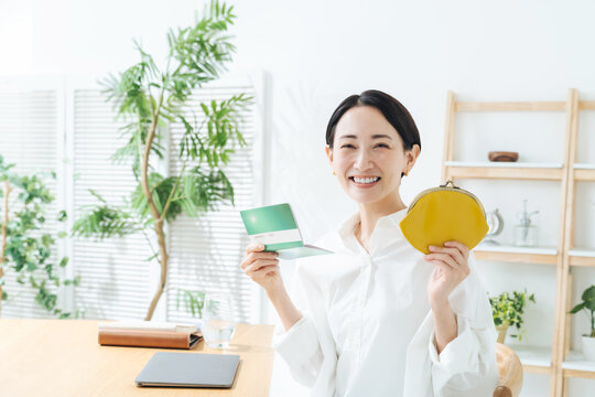 笑顔で通帳と財布を持つ女性。貯金、マネー、投資、資産運用、財テク、ショッピング、お得、セール、お金