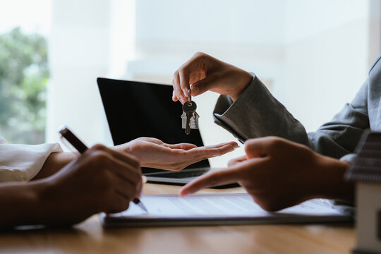 Real estate agent handing over house keys after signing a property agreement, symbolizing home ownership, closing deals, and successful transactions.
