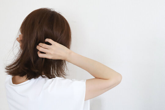 寝ぐせや髪の乱れを気にする女性の後ろ姿
