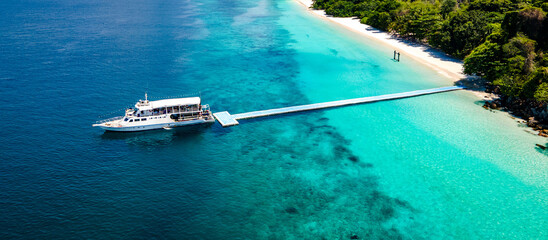 Aerial drone view of tropical landscape over Madam Beach of Nyaung Oo Phee Island with tour boat anchoring on the floating dock in the Mergui Archipelago, Myanmar. Beautiful Andaman sea in Burma © zephyr_p
