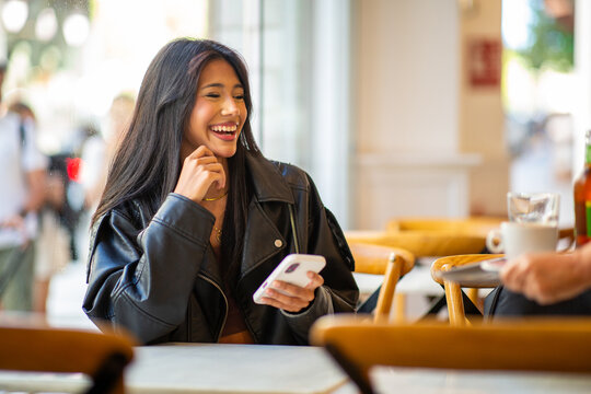Smiling woman using smartphone in cozy cafe setting