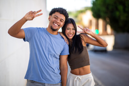 Happy couple making peace signs outdoors