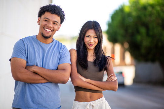 Confident young couple standing with arms crossed outdoors