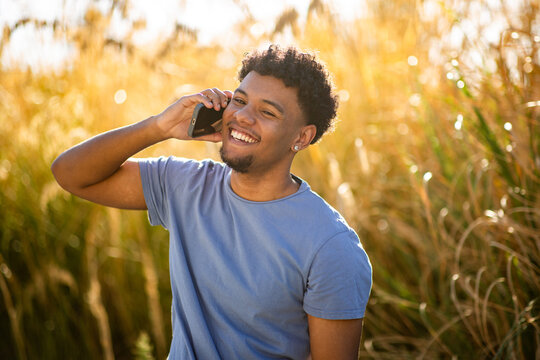 Smiling man talking on smartphone in golden field