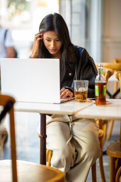 Focused woman working on laptop in cafe environment