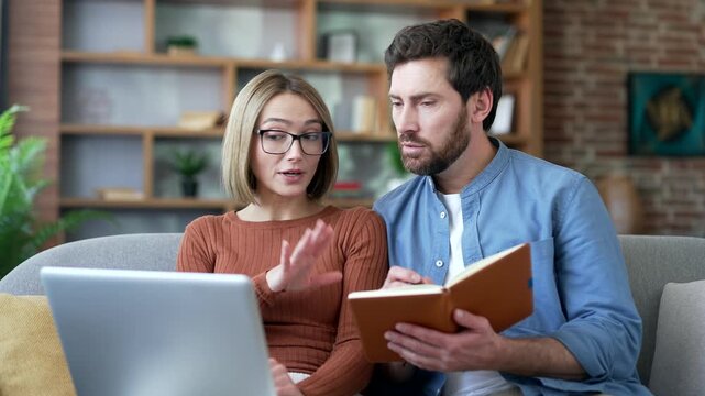 Family couple watching video call training notes in notebook looking at laptop computer screen sitting in living room at home. Husband and wife listening remote training, webinar or course. Close up