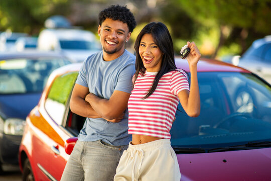 Excited young couple celebrating new car purchase outdoors