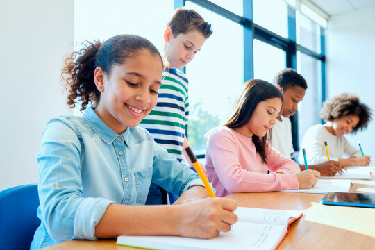 Multiethnic schoolchildren studying and writing in classroom, supporting teamwork, concentration, education progress. Ideal for school marketing, tutoring, learning campaigns