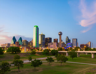 Obraz premium A stunning twilight view of the Dallas skyline showcases its iconic architecture and vibrant cityscape, bathed in the soft hues of the setting sun.