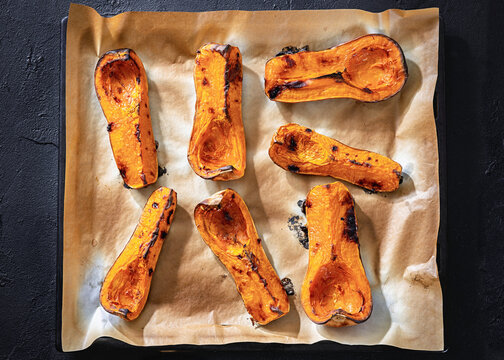 Baked butternut squash halves on a paper