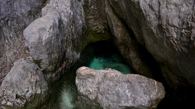 Turquoise spring water emerging from karst cave at the source of the Soca River, establishing tilt up