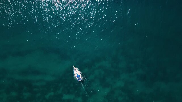 White sailing yacht leaving a soft wake in the clear blue Adriatic Sea, Croatia. Sunny day, bird eye view