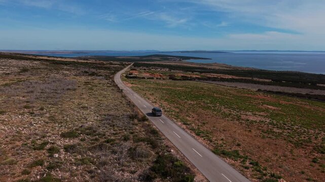 Camper van on its scenic drive along the Mediterranean Adriatic coast. Aerial view car tracking.