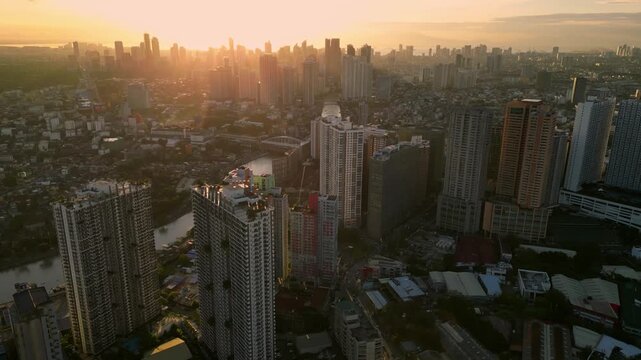 Forward aerial shot flying from Kapitolyo in Pasig City toward Rockwell Center in Makati Philippines showcasing dense urban development and modern city infrastructure during sunset.