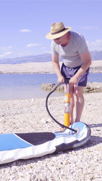 Person inflating sup board with pump at the beach