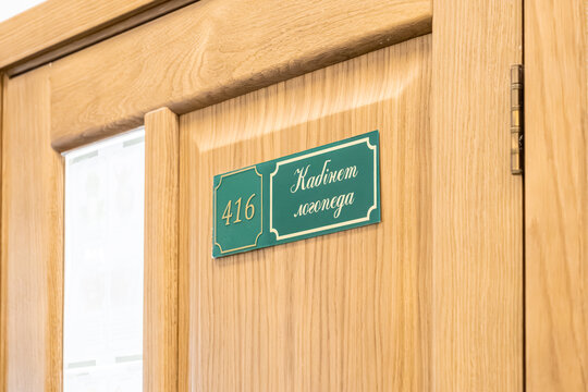 Green speech therapist office sign with number 416 mounted on a light wood door in a medical or educational institution, conveying professional guidance and health support service